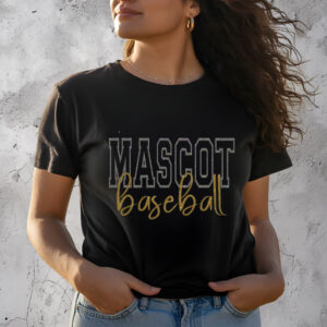 Woman wearing stylish black "Mascot Baseball" t-shirt with gold and white lettering, standing against a textured gray wall