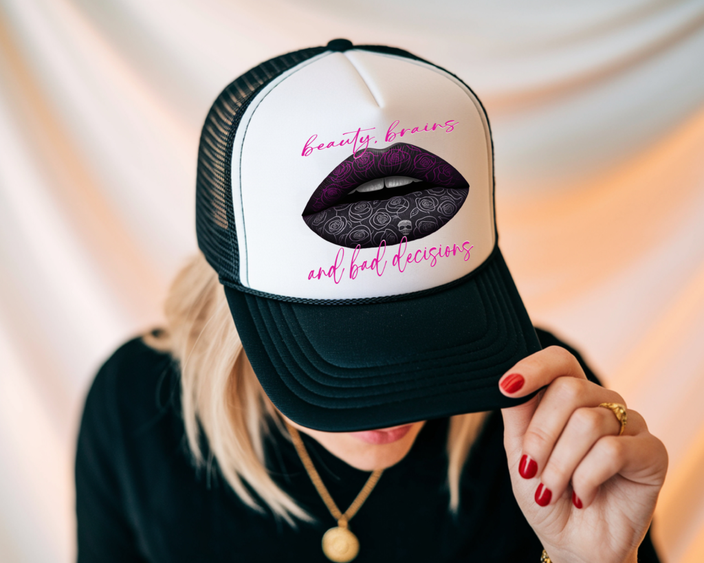 Trucker hat featuring a bold graphic of purple and black patterned lips with the phrase “beauty, brains and bad decisions.