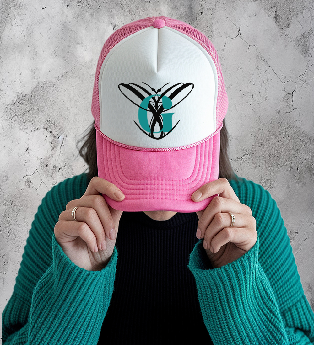 Person wearing a pink and white trucker hat featuring a custom monogram design on the front panel.