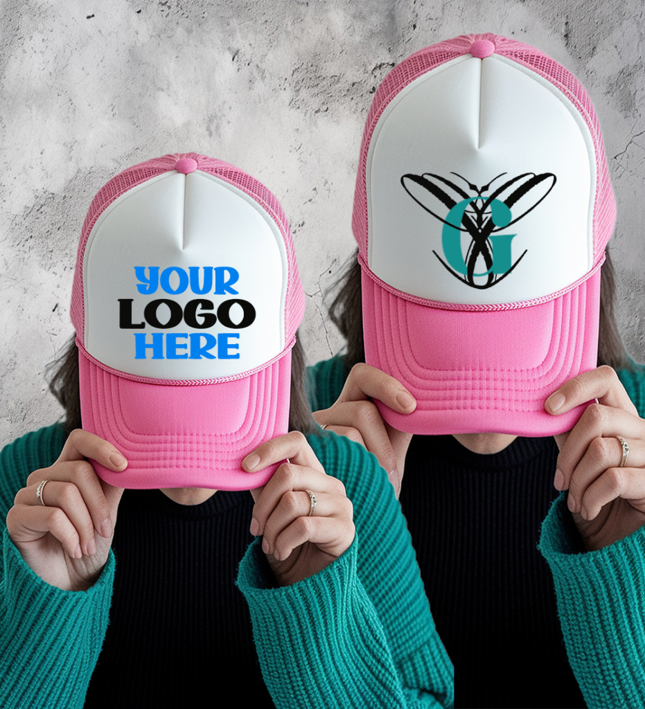 Two pink and white customizable trucker hats shown on a person, one with placeholder text “Your Logo Here” and the other with a custom monogram design.