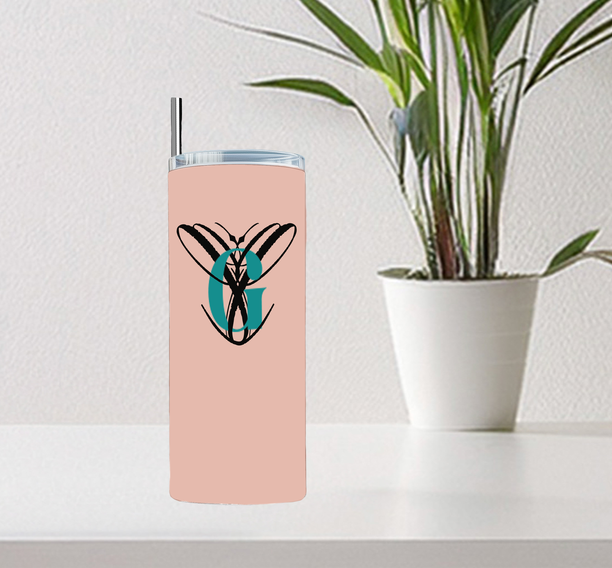 Pink 20oz skinny tumbler with a business logo monogram displayed on a desk beside a potted plant.