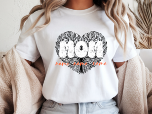 White women's custom t-shirt featuring a black heart-shaped tree of life design with distressed "Mom" lettering and 3 personalized children's name written in orange script below, worn by a woman with a cozy neutral aesthetic background.