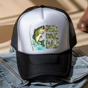 Black and white trucker hat with a custom "Reel Cool Dad" fishing design featuring a jumping bass, fishing rod, and camo-style lettering.