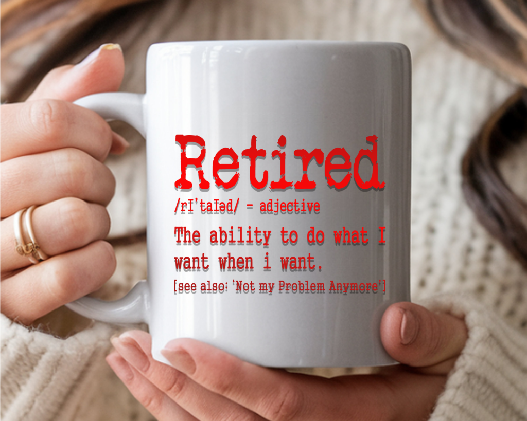 White coffee mug with sarcastic retirement definition: "Retired – The ability to do what I want when I want," in a red gradient color held in two hands against a cozy sweater background